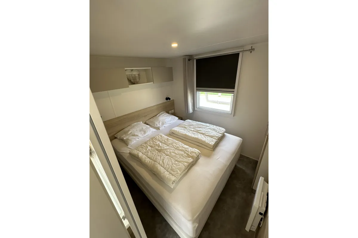 Grote slaapkamer met ruime boxspring en kledinkasten.