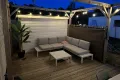 Terras met loungebank, hangmat en eettafel.